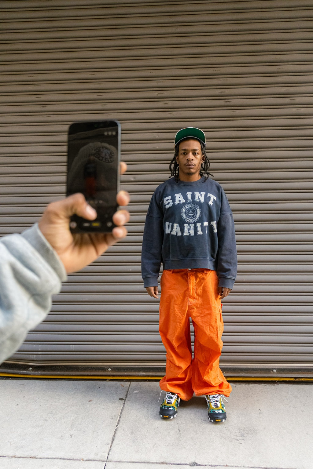 Model wearing blue washed Saint Vanity university crewneck with orange trousers